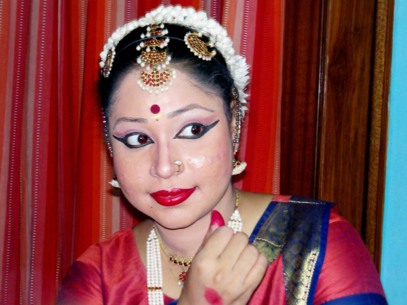A solo Indian classical dancer performing with expressive hand gestures and graceful posture, wearing vibrant traditional costume.