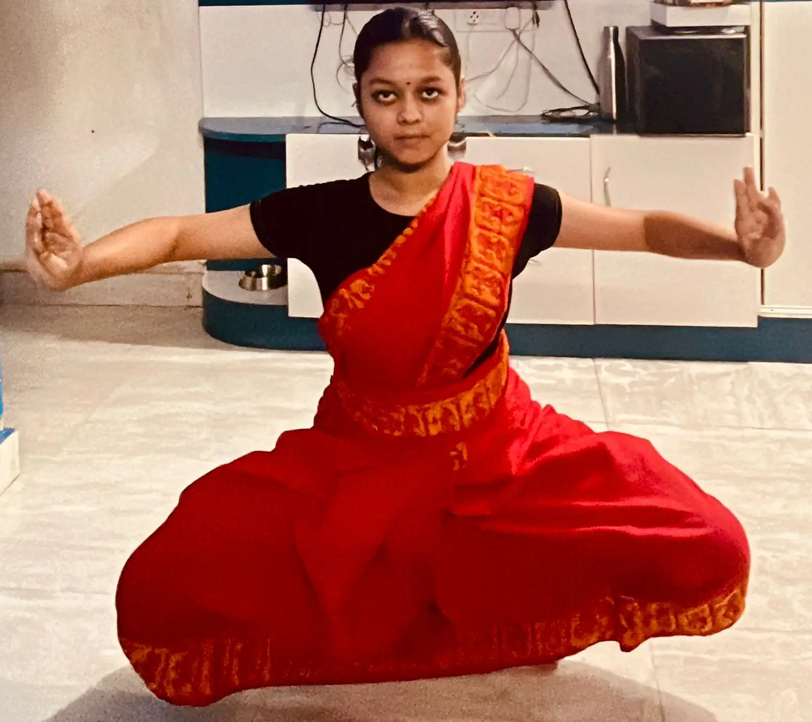A dedicated Odissi dance student practicing graceful movements in a simple traditional cotton costume used for training sessions.